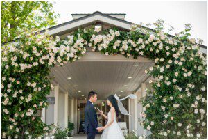 Couple holding hands beneath rose arch at San Ramon wedding.
